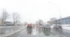 Cars on the road through a rainy car windshield.