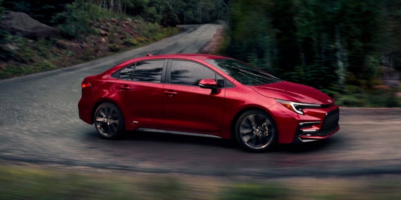 Red Toyota Corolla Hybrid in motion on the road