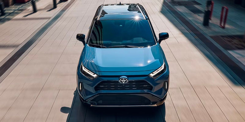 Blue Toyota RAV4 Hybrid on city street, top view.